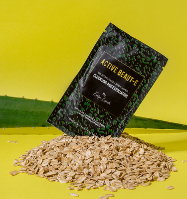 The best cleansing and exfoliating wipes placed on top of a pile of oats in front of an aloe leaf.