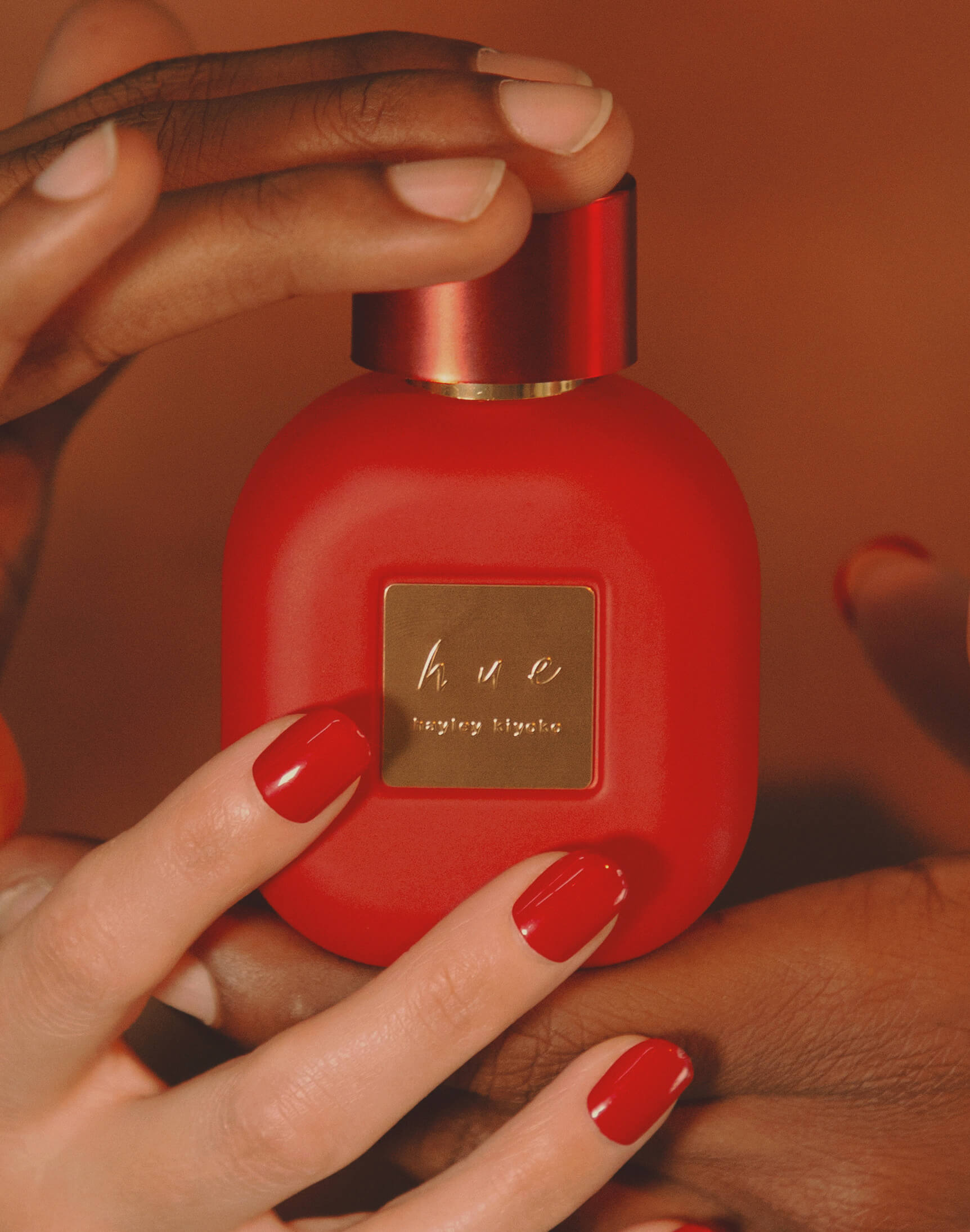 Hands reaching out to grab best-selling perfume, Hue by Hayley Kiyoko.