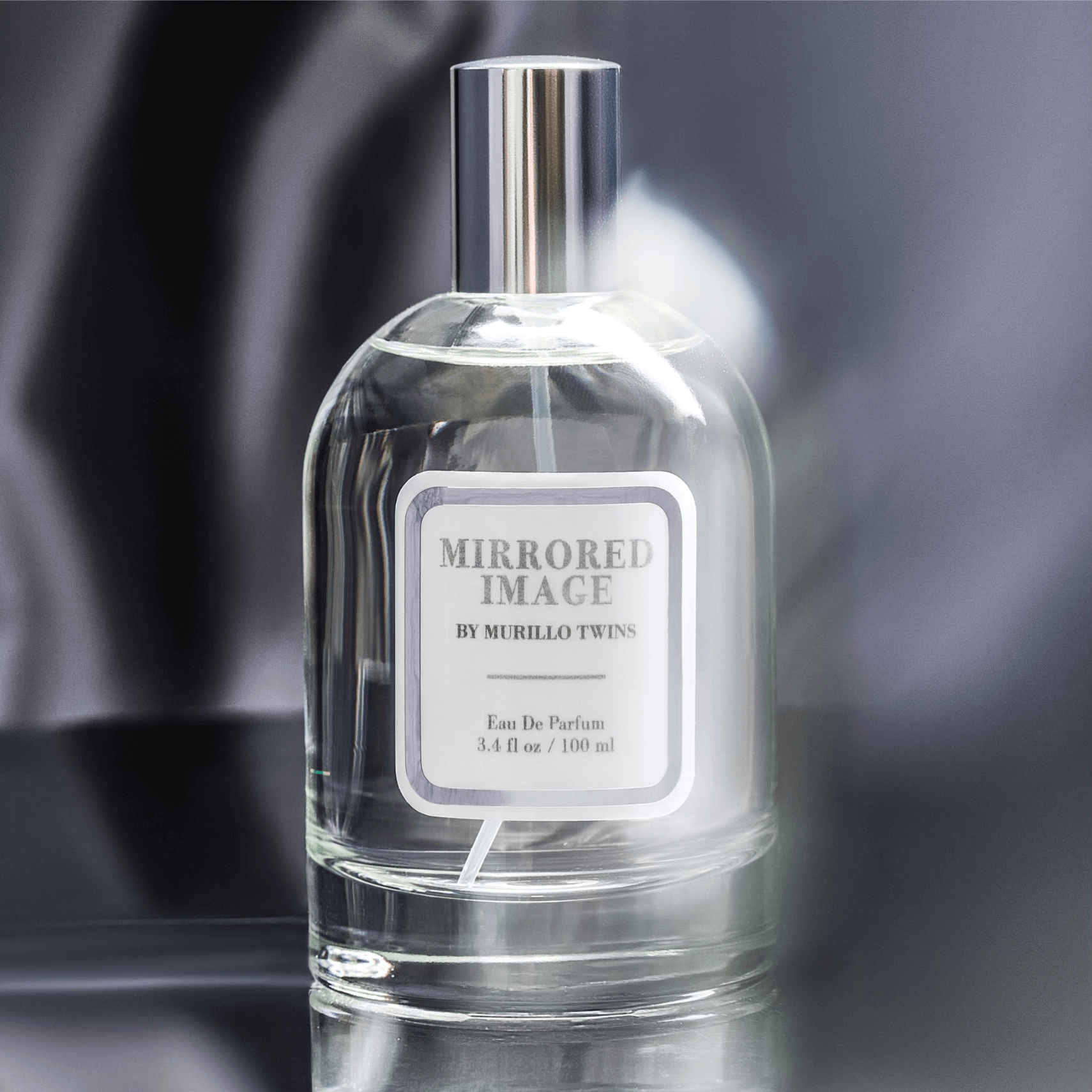 Mirrored Image fragrance by celebrity sisters, Briana and Brittany Murillo, displayed in a mysterious, moody setting.