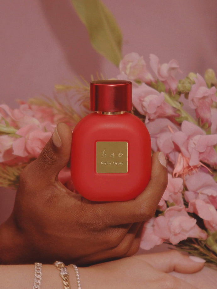 Someone holding a celebrity perfume bottle against a flower background.