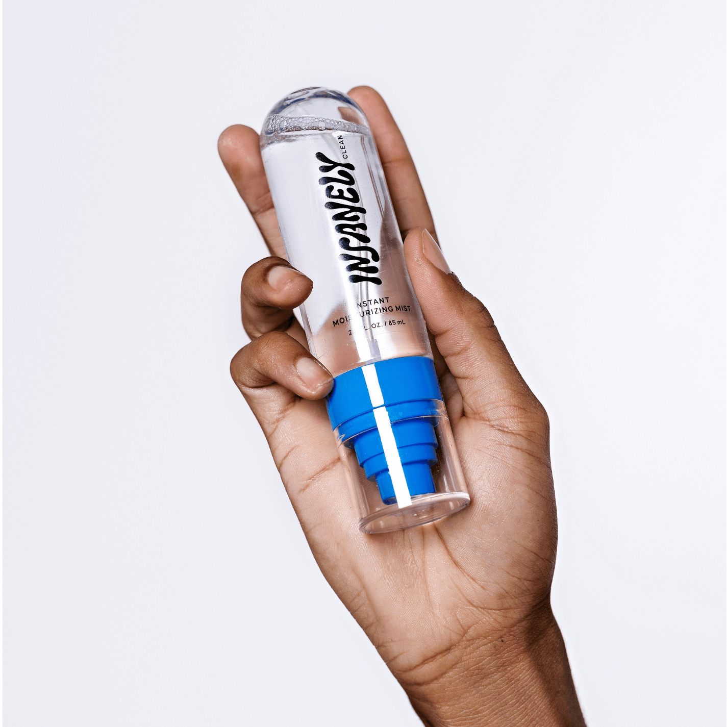The most minimal men's facial hydrating mist being held up by a man's hand.